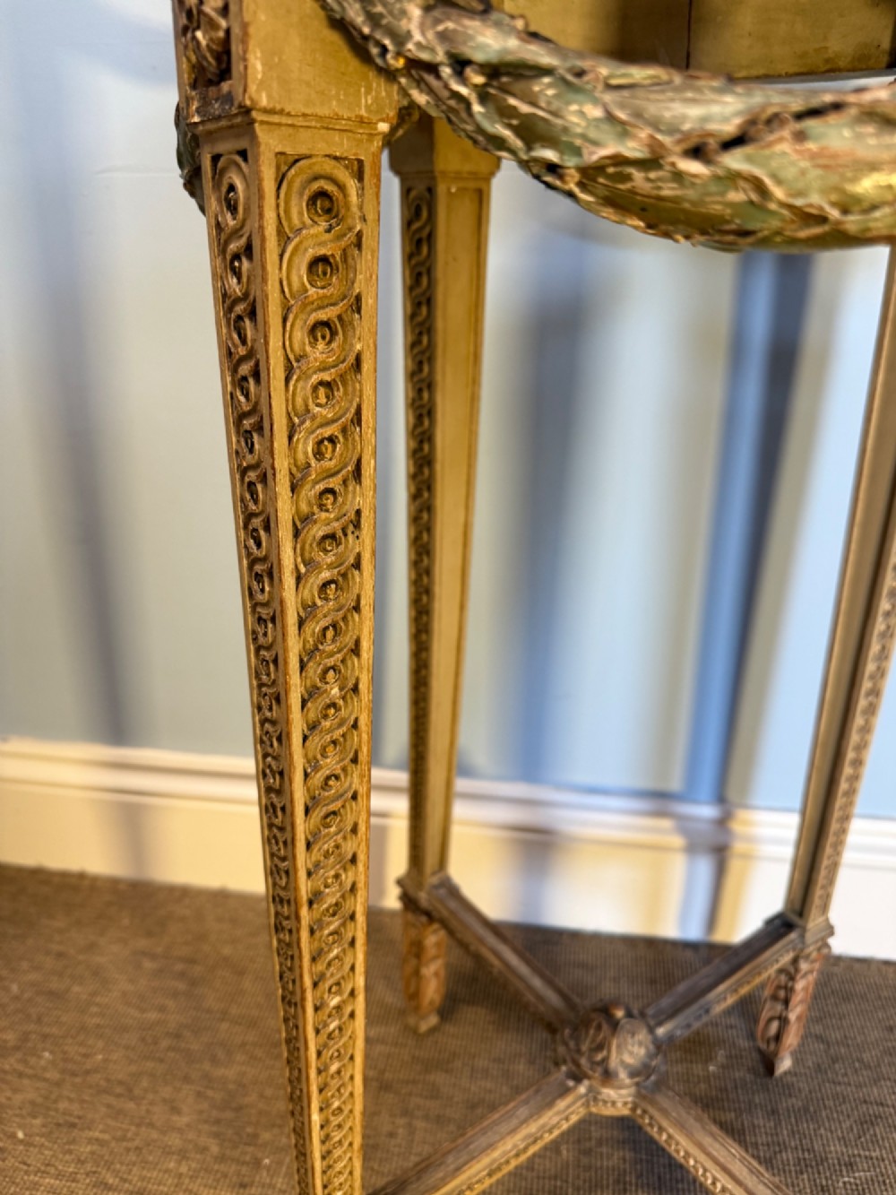 A tall 19th-century French Neoclassical style plant stand featuring a circular grey marble top, carved cream and parcel-gilded legs with swags, and a central X-stretcher. View IV