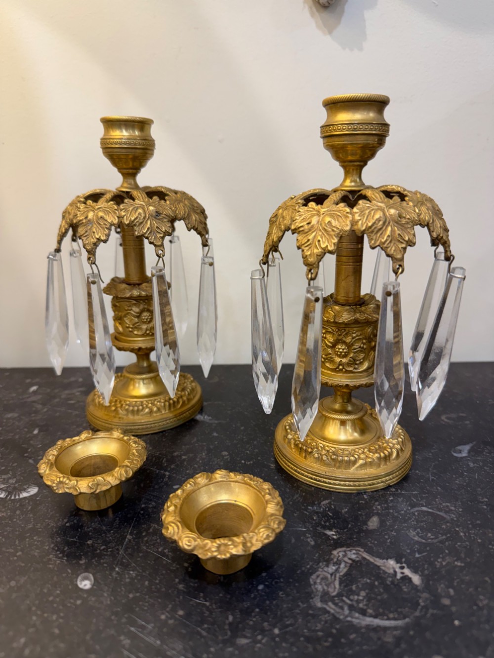 A pair of 19th-century gilt bronze ormolu candlesticks featuring acanthus leaf crowns and suspended clear crystal prism lustres. View V