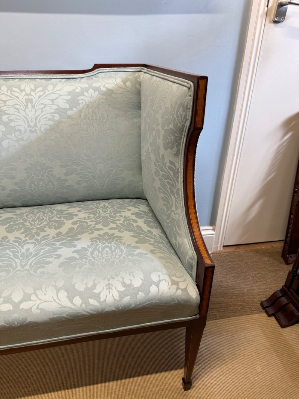 An Edwardian two-seater mahogany sofa upholstered in light blue damask fabric with satinwood crossbanding along the frame. View II