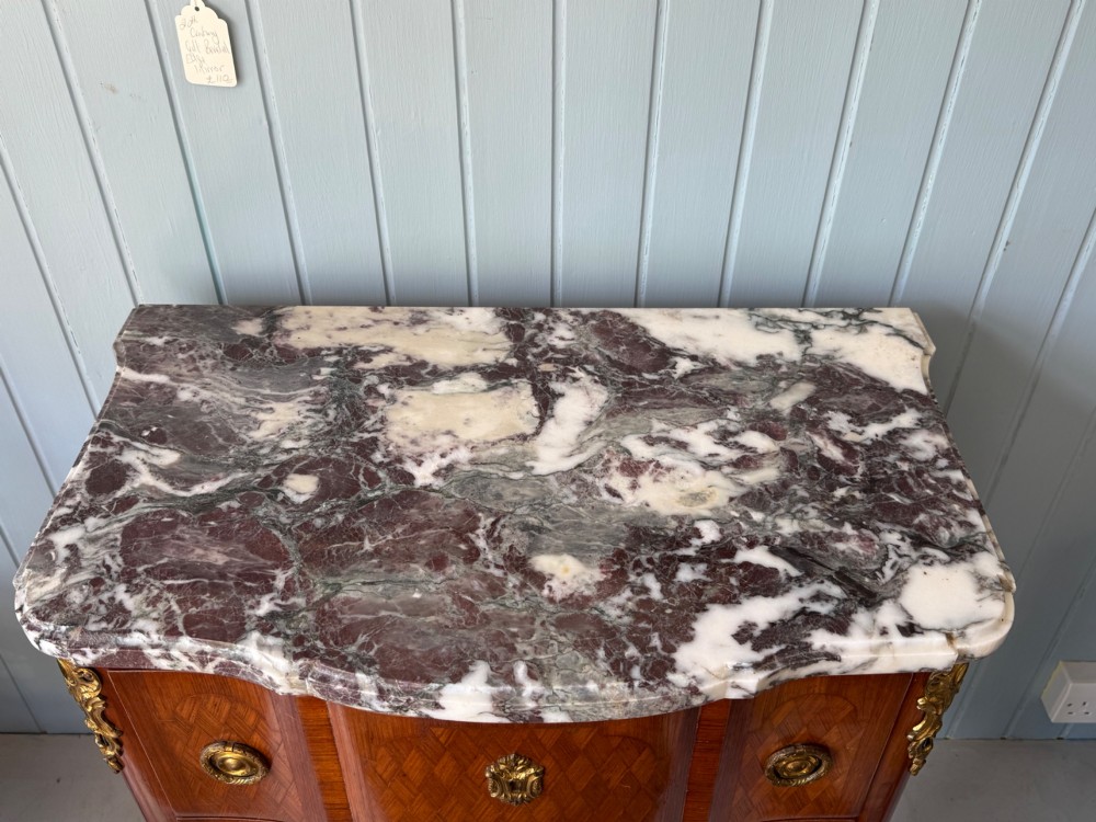 A mid 19th-century French commode featuring a marble top, parquetry wood veneer, two drawers with gilt bronze handles, and cabriole legs. View II