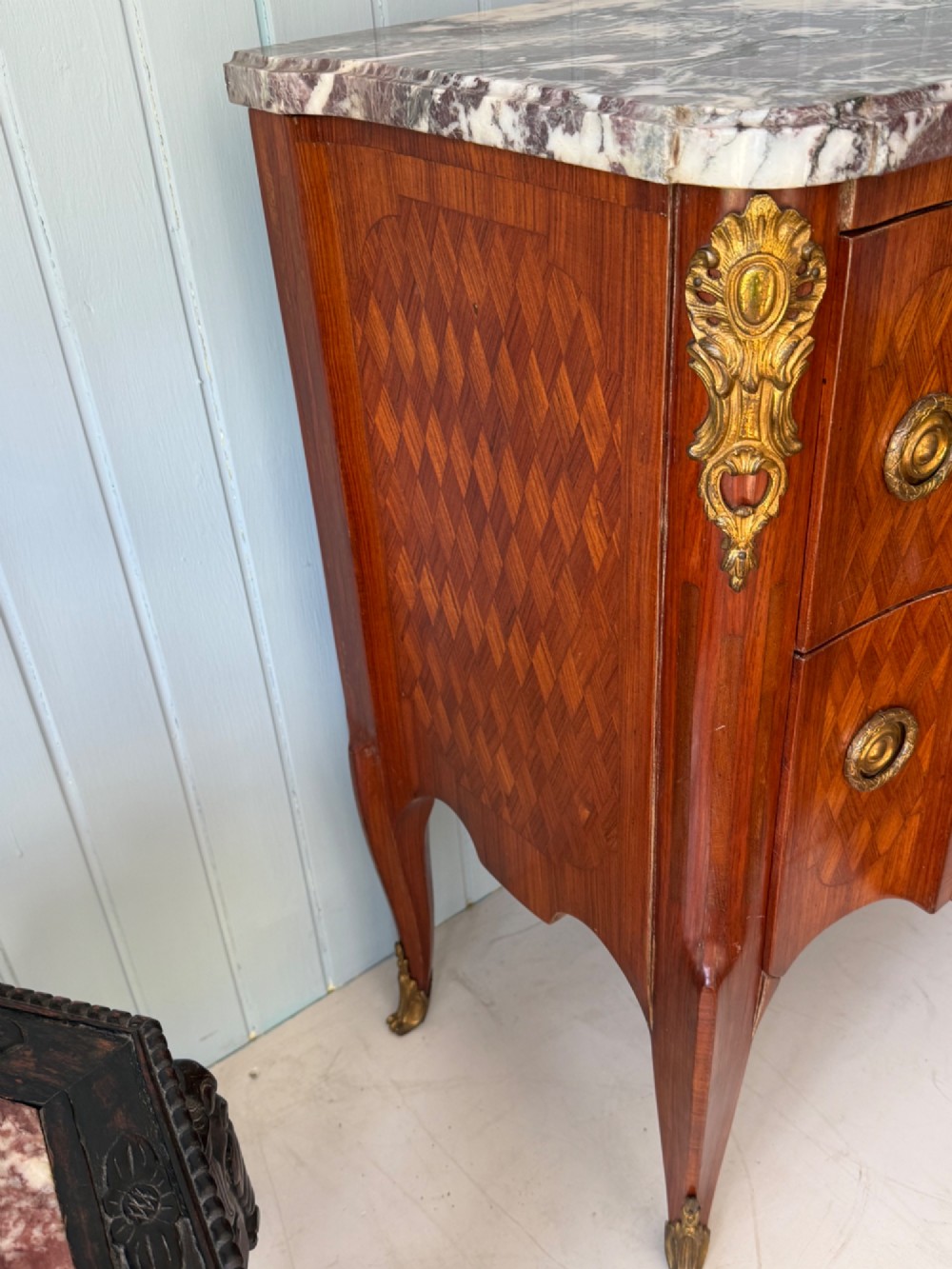 A mid 19th-century French commode featuring a marble top, parquetry wood veneer, two drawers with gilt bronze handles, and cabriole legs. View V