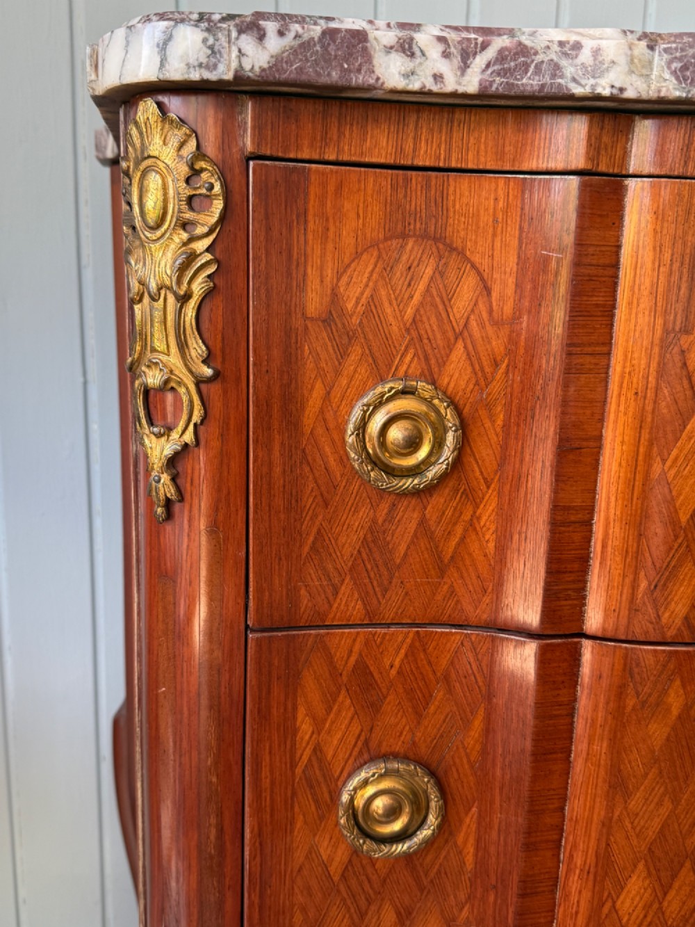A mid 19th-century French commode featuring a marble top, parquetry wood veneer, two drawers with gilt bronze handles, and cabriole legs. View VI