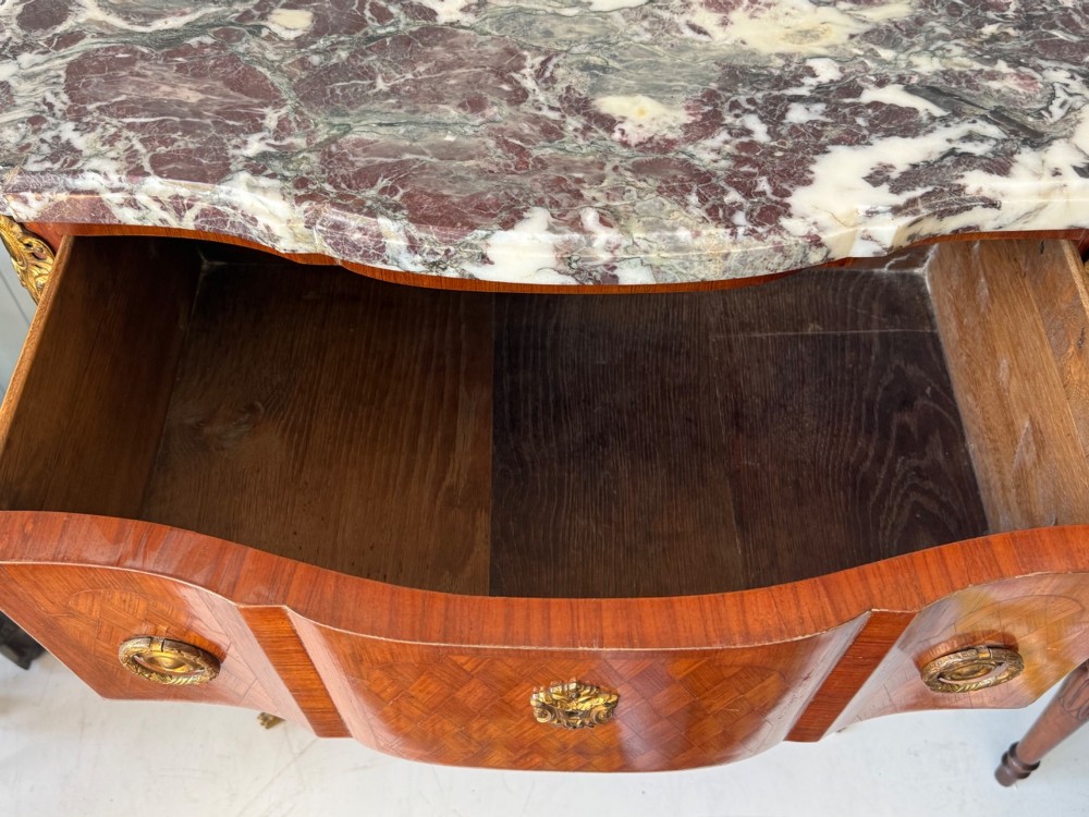 A mid 19th-century French commode featuring a marble top, parquetry wood veneer, two drawers with gilt bronze handles, and cabriole legs. View IX