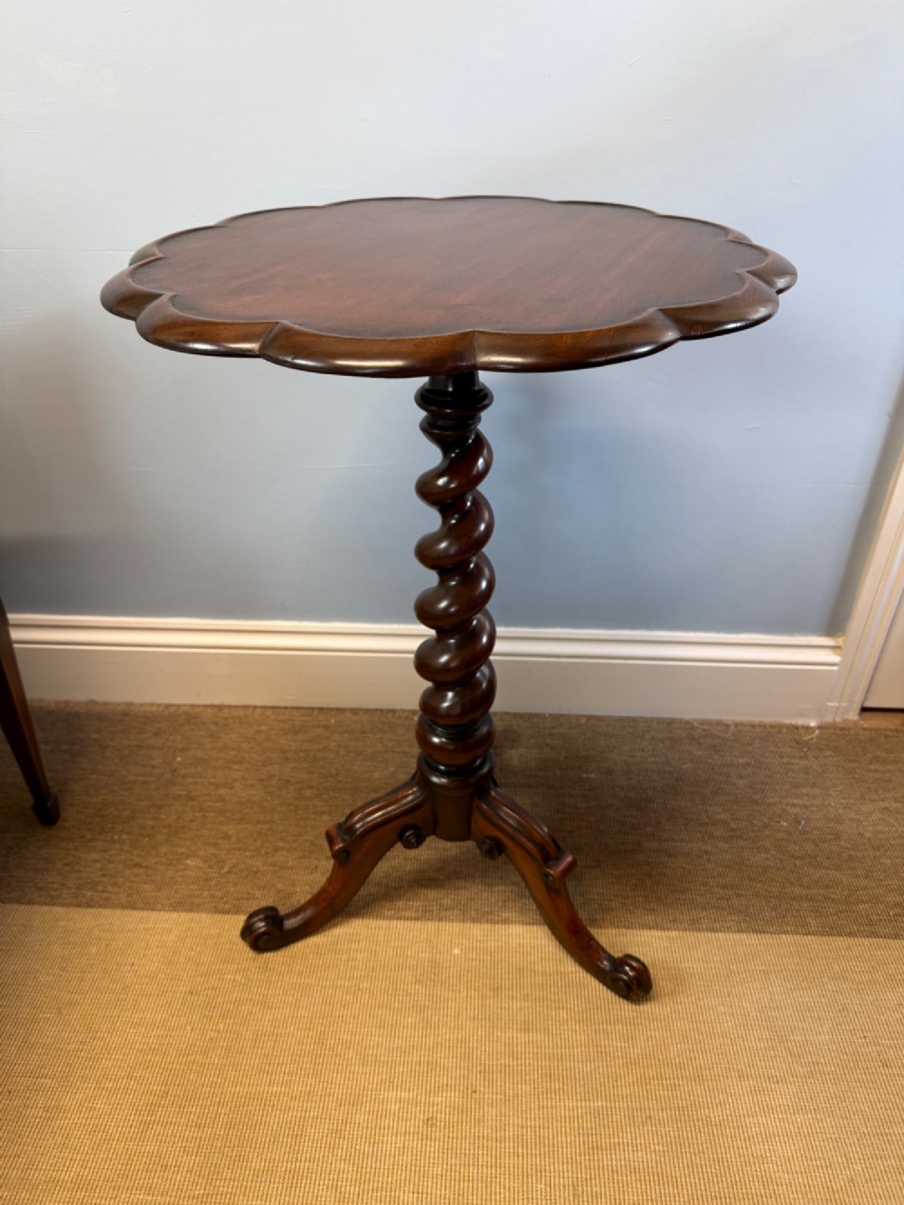 A 19th-century mahogany tripod side table featuring a scalloped piecrust edge top, a spiral barley twist column stem, and carved cabriole legs.