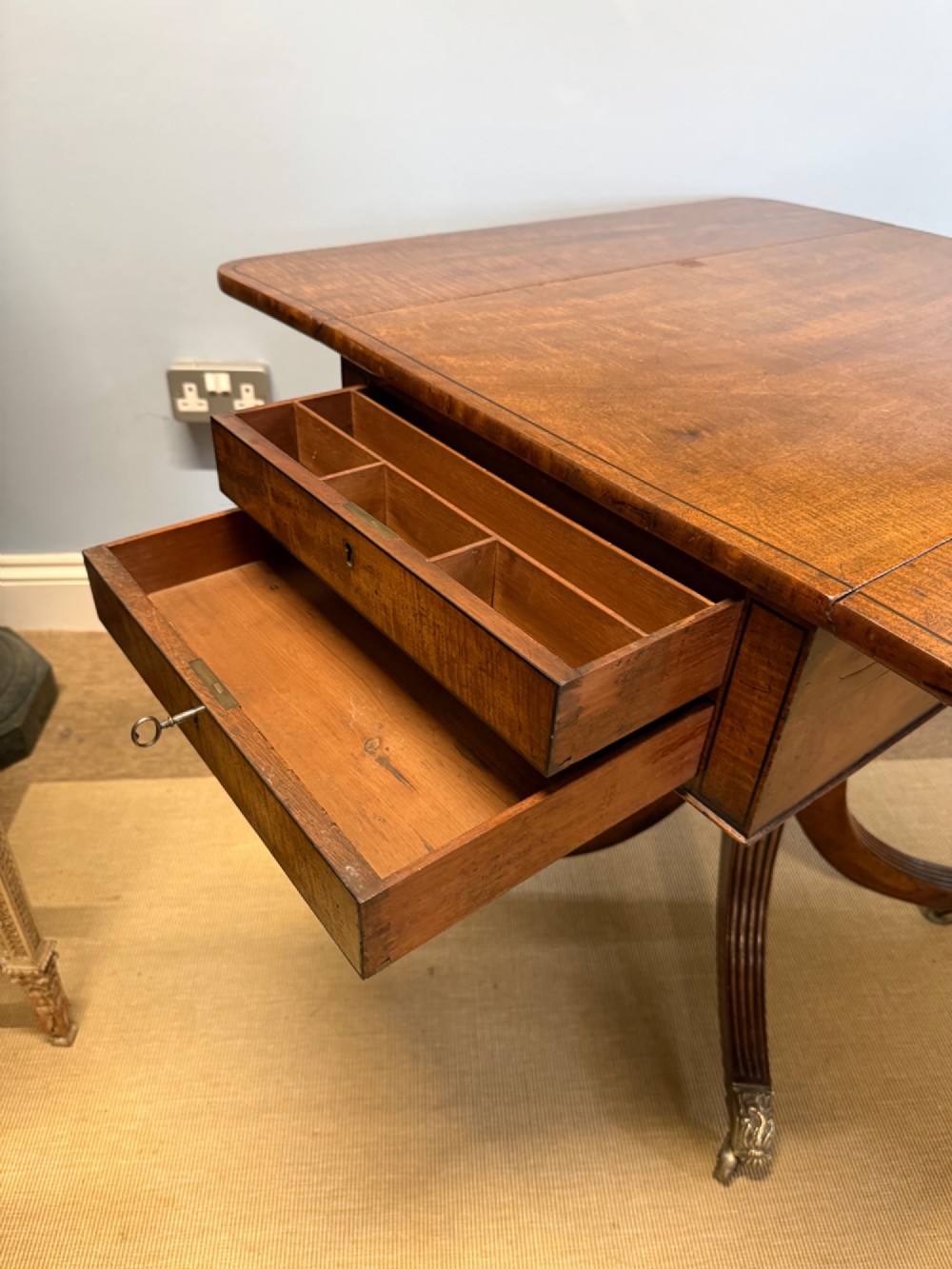 A Regency mahogany drop-leaf table featuring a turned central column, reeded quadform legs, and brass lion paw castors. View V
