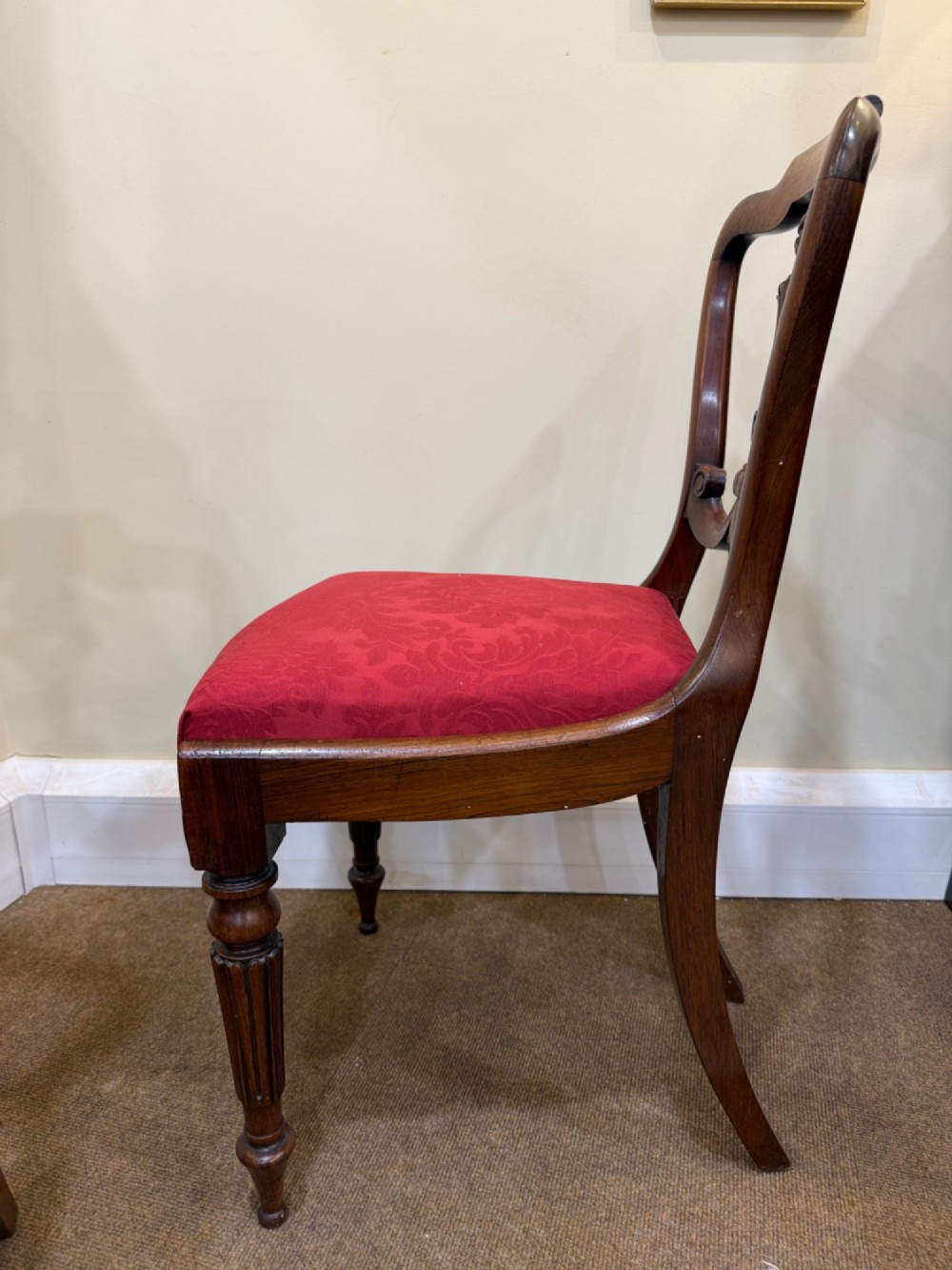 A set of four Victorian rosewood balloon-back dining chairs with carved centre splats and individual damask upholstered seats in yellow, red, cream, and blue. View II