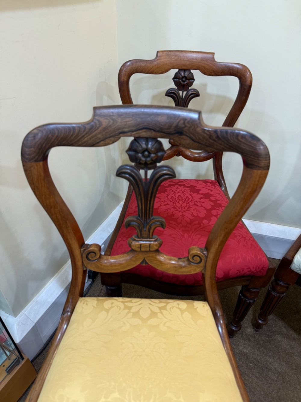 A set of four Victorian rosewood balloon-back dining chairs with carved centre splats and individual damask upholstered seats in yellow, red, cream, and blue. View III