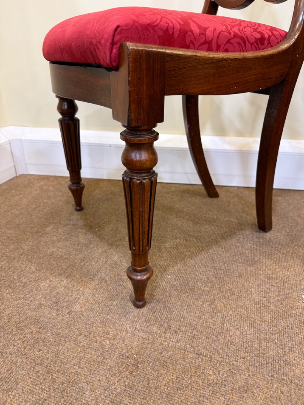 A set of four Victorian rosewood balloon-back dining chairs with carved centre splats and individual damask upholstered seats in yellow, red, cream, and blue. View IV