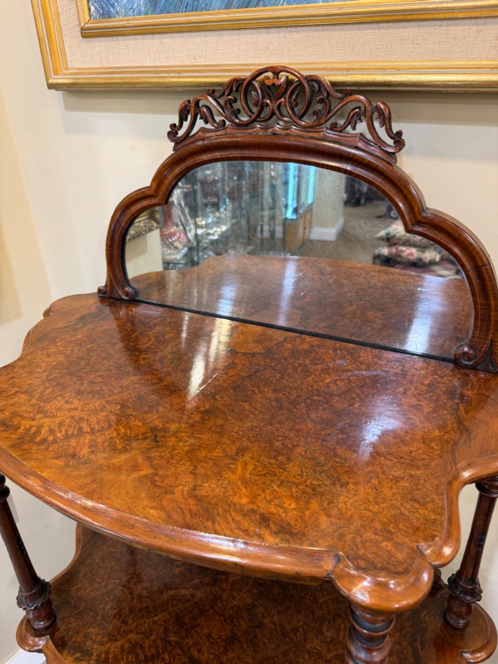 A three-tiered Victorian burr walnut whatnot featuring a carved fretwork upstand with a central arched mirror, turned spindle supports, and a base drawer on small castors. View II