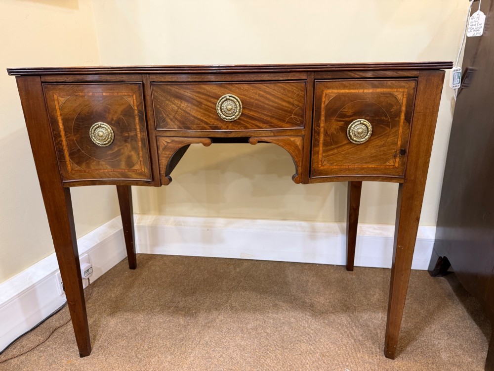 An Edwardian mahogany side cabinet featuring satinwood inlay, brass ring handles, three drawers, and square tapered legs.