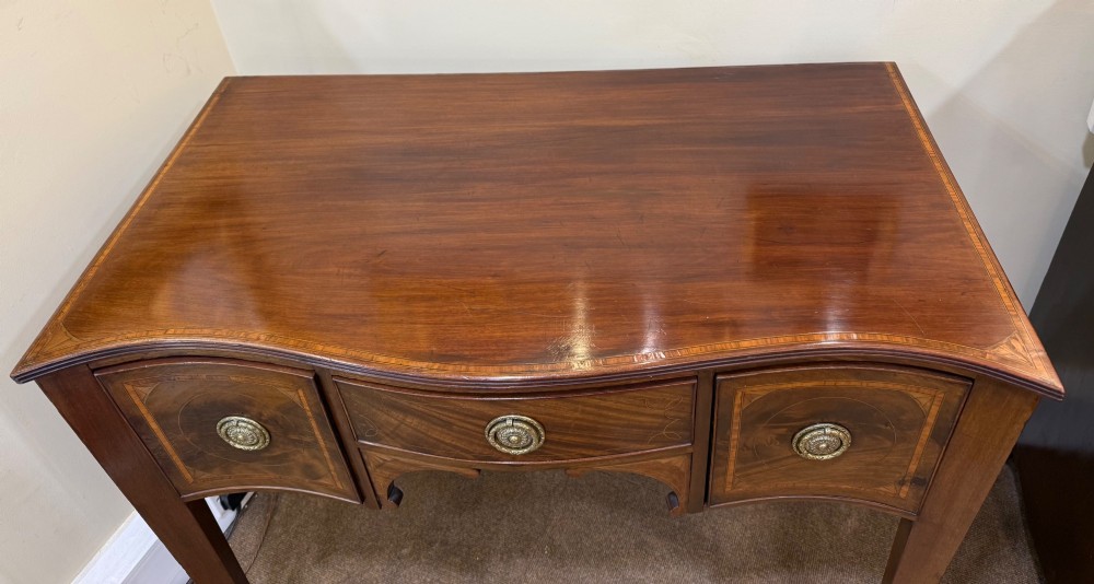 An Edwardian mahogany side cabinet featuring satinwood inlay, brass ring handles, three drawers, and square tapered legs. View II