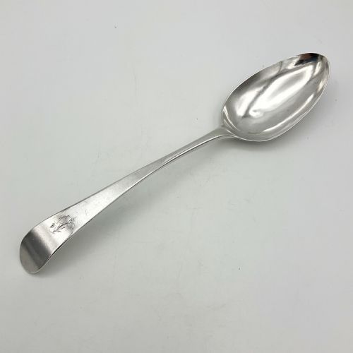 fig 1. A Georgian sterling silver serving spoon with an oval bowl and a down-curved handle featuring an engraved monogram.