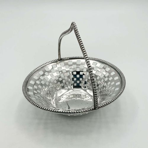 fig 1. An Edwardian sterling silver basket with a pierced square lattice bowl, beaded rim, and an arched beaded handle.