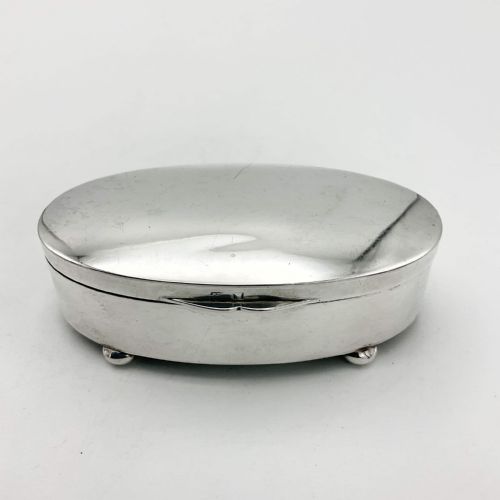 fig 1. A polished oval sterling silver jewellery box with a hinged lid resting on four small rounded feet.