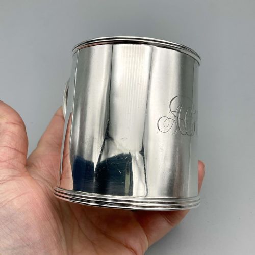 fig 1. An Edwardian sterling silver christening cup with a cylindrical body, moulded rim, strap handle, and subtle monogram engraving.