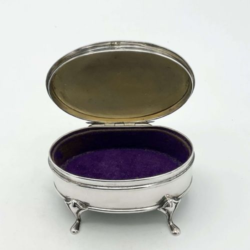 fig 2. An oval sterling silver jewellery box featuring an engraved hinged lid, a foliage pattern border, and four curved cabriole feet.