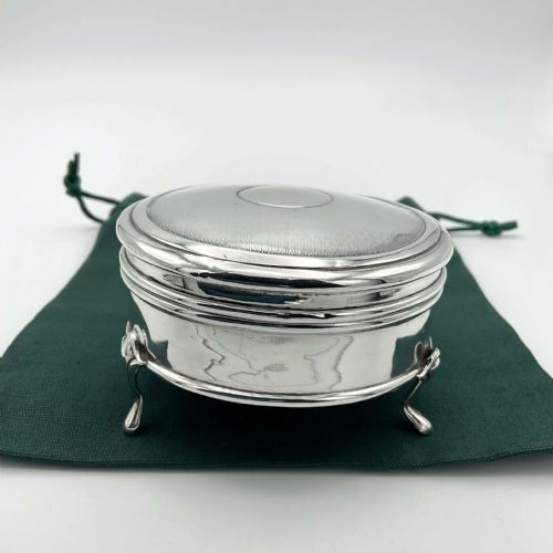 fig 1. A circular sterling silver jewellery box with engine-turned lid decoration and a central round cartouche, supported on three small feet.