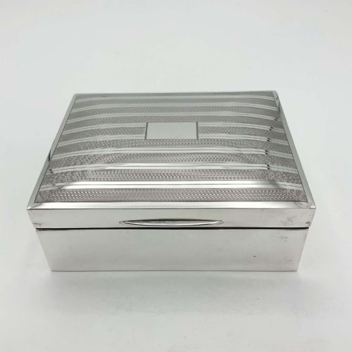 fig 1. A rectangular Art Deco sterling silver box featuring an engine-turned striped pattern on the lid and a central rectangular vacant cartouche.