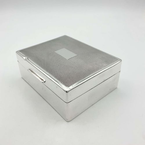 fig 1. A square sterling silver box featuring an engine-turned pattern on the lid with a unengraved central rectangular cartouche.