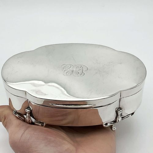fig 2. An oval 1918 sterling silver jewellery box featuring scrolled cabriole legs and an engraved monogram on the hinged lid.