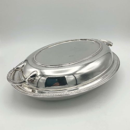 fig 1. A silver-plated oval entree dish featuring a fitted cover with beaded rim details and two side handles.