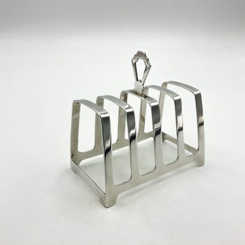 fig 1. An Art Deco sterling silver toast rack featuring four slots with arched dividers, a central geometric handle, and visible hallmarks along the base.