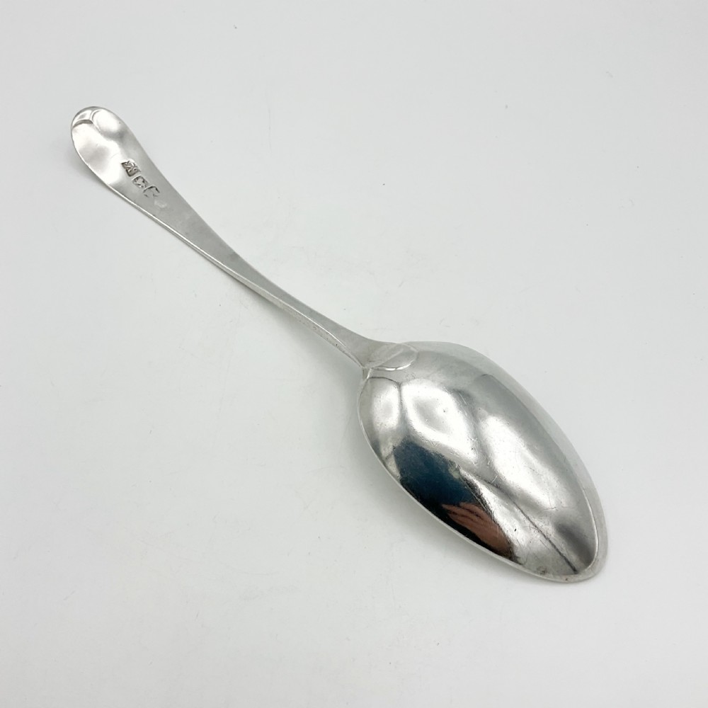 A Georgian sterling silver serving spoon with an oval bowl and a down-curved handle featuring an engraved monogram. View III