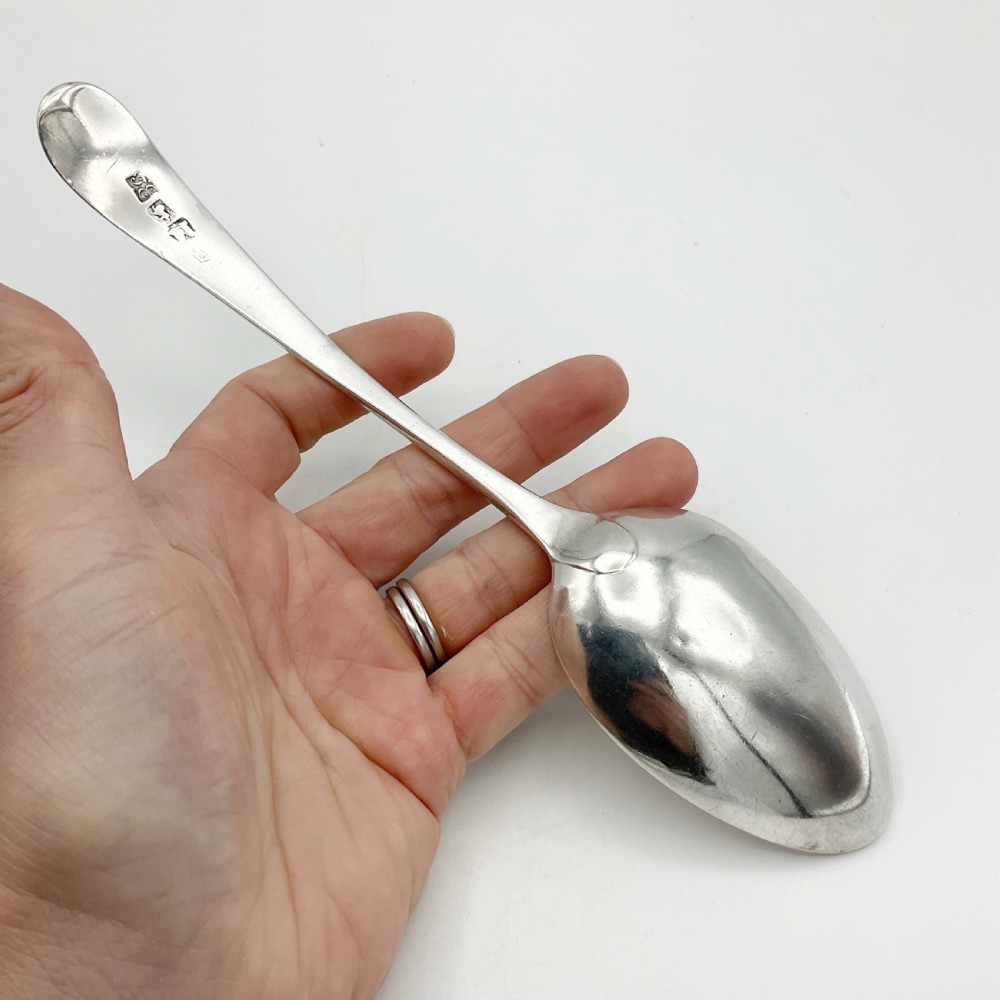 A Georgian sterling silver serving spoon with an oval bowl and a down-curved handle featuring an engraved monogram. View IV