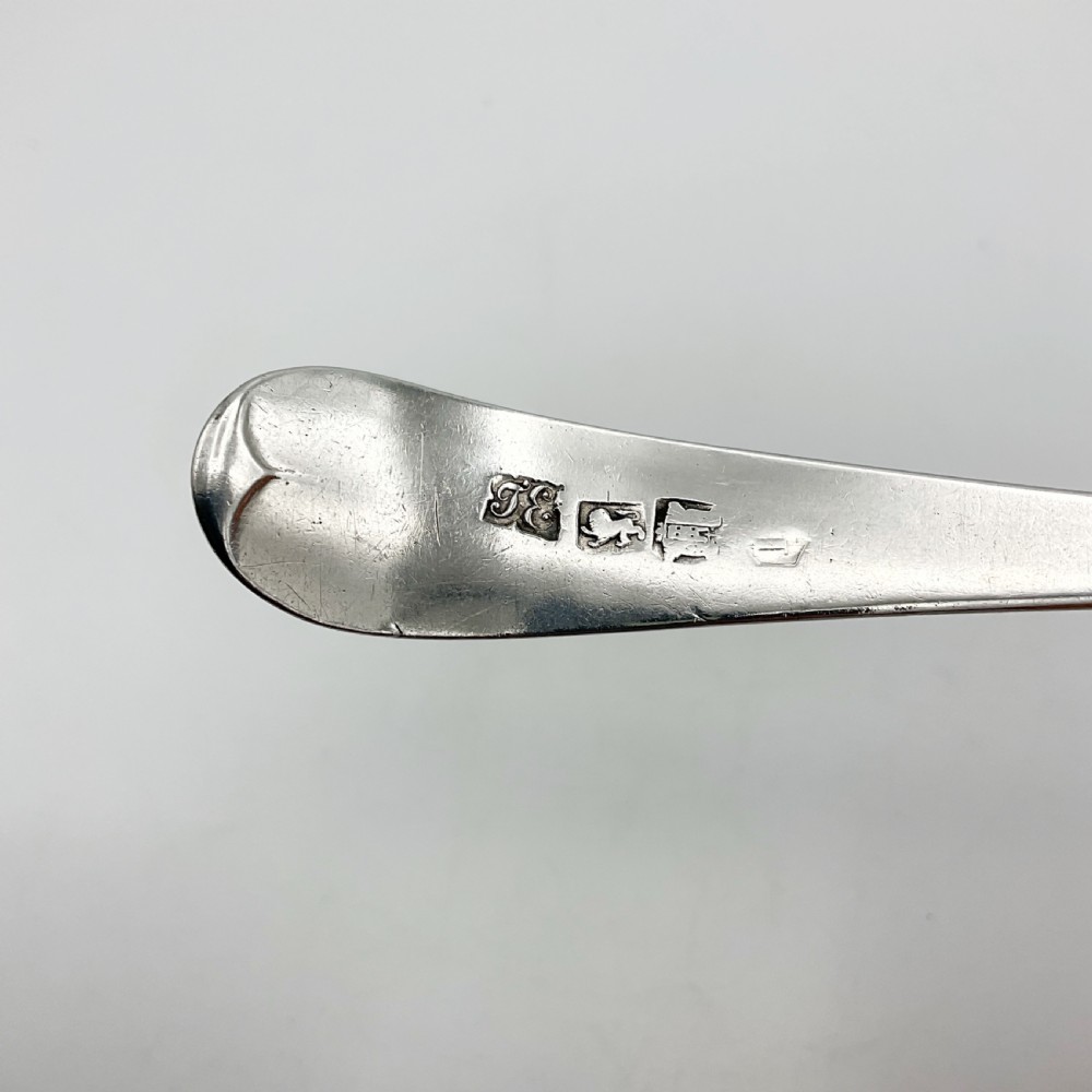 A Georgian sterling silver serving spoon with an oval bowl and a down-curved handle featuring an engraved monogram. View VI