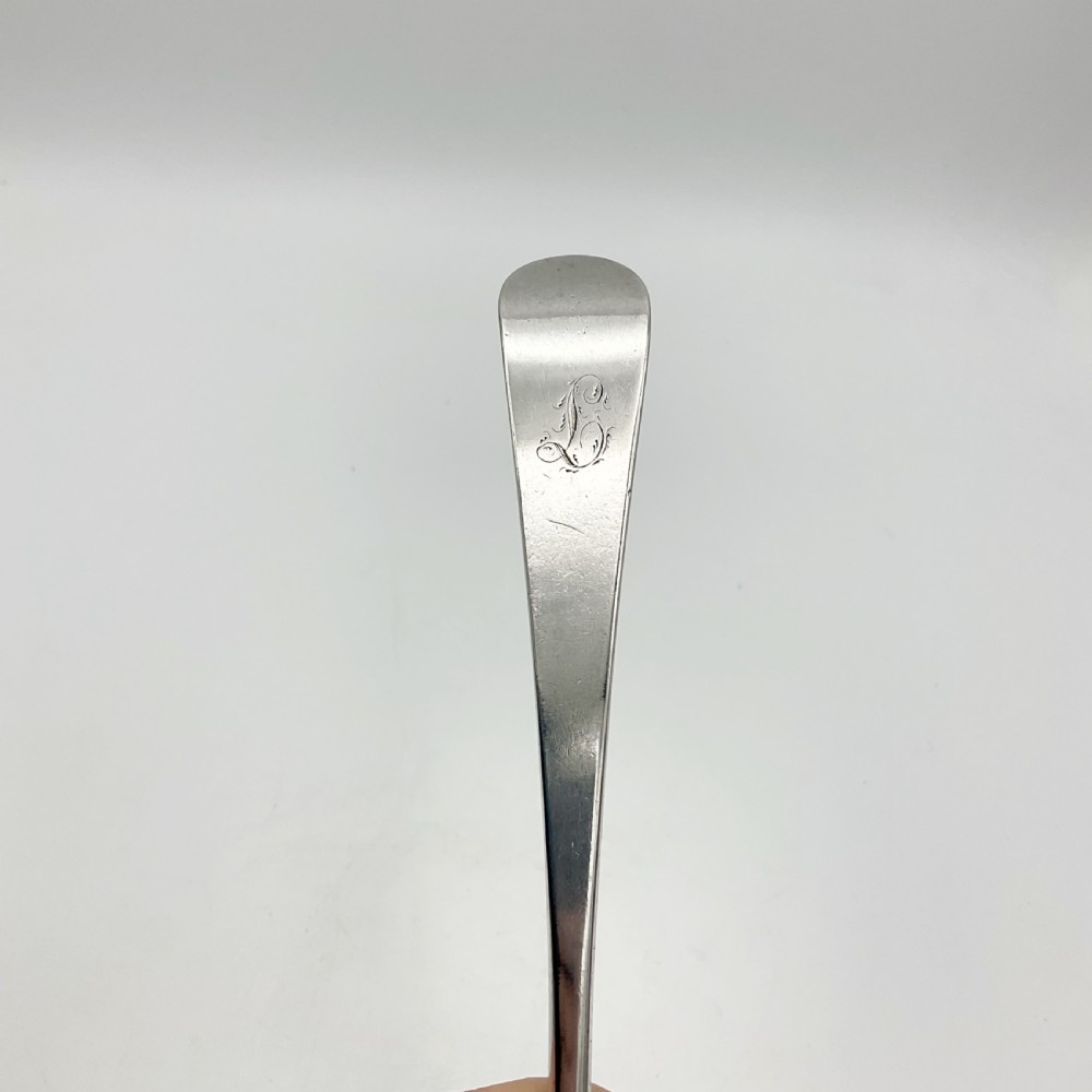 A Georgian sterling silver serving spoon with an oval bowl and a down-curved handle featuring an engraved monogram. View VII