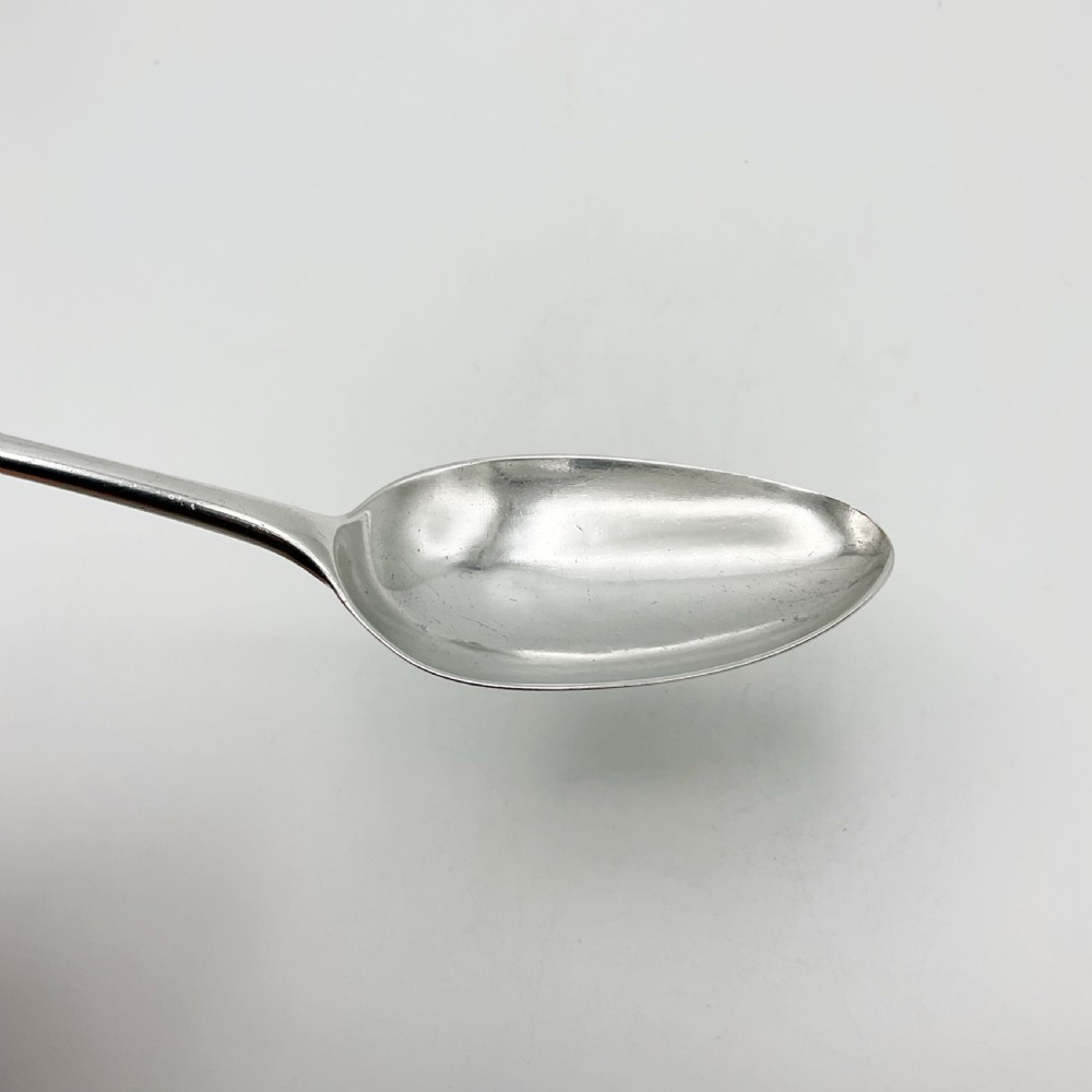 A Georgian sterling silver serving spoon with an oval bowl and a down-curved handle featuring an engraved monogram. View VIII