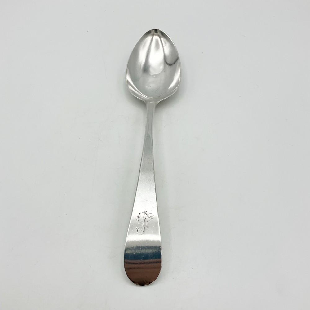 A Georgian sterling silver serving spoon with an oval bowl and a down-curved handle featuring an engraved monogram. View XI