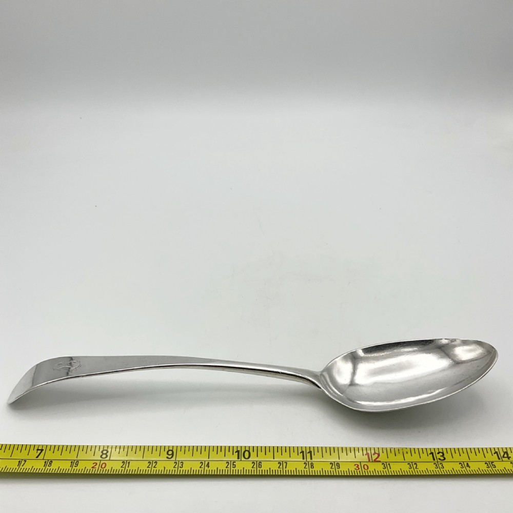 A Georgian sterling silver serving spoon with an oval bowl and a down-curved handle featuring an engraved monogram. View XII