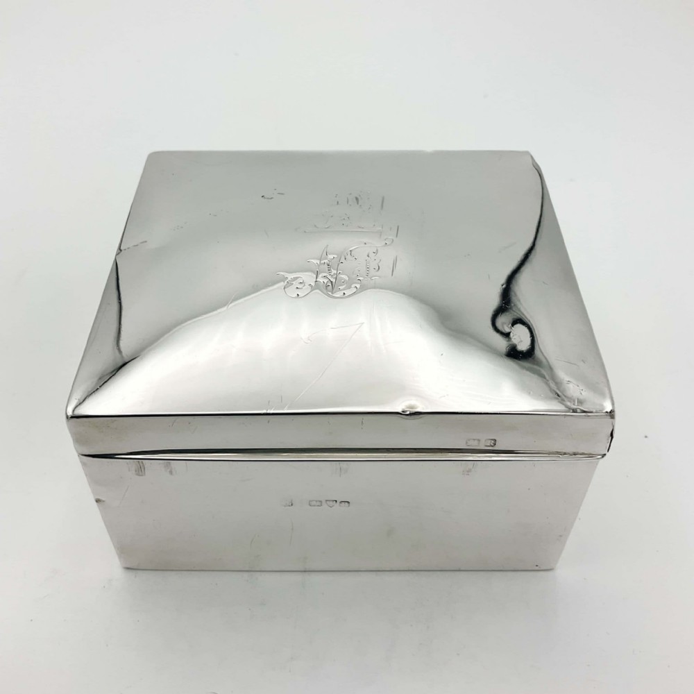 A square sterling silver box with a slightly domed lid, engraved monogram, and visible hallmark stamps on the front edge.