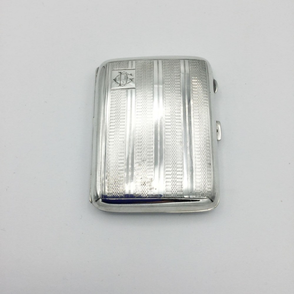 A rectangular 1930s Art Deco sterling silver case decorated with engine-turned linear patterns and a monogram cartouche.