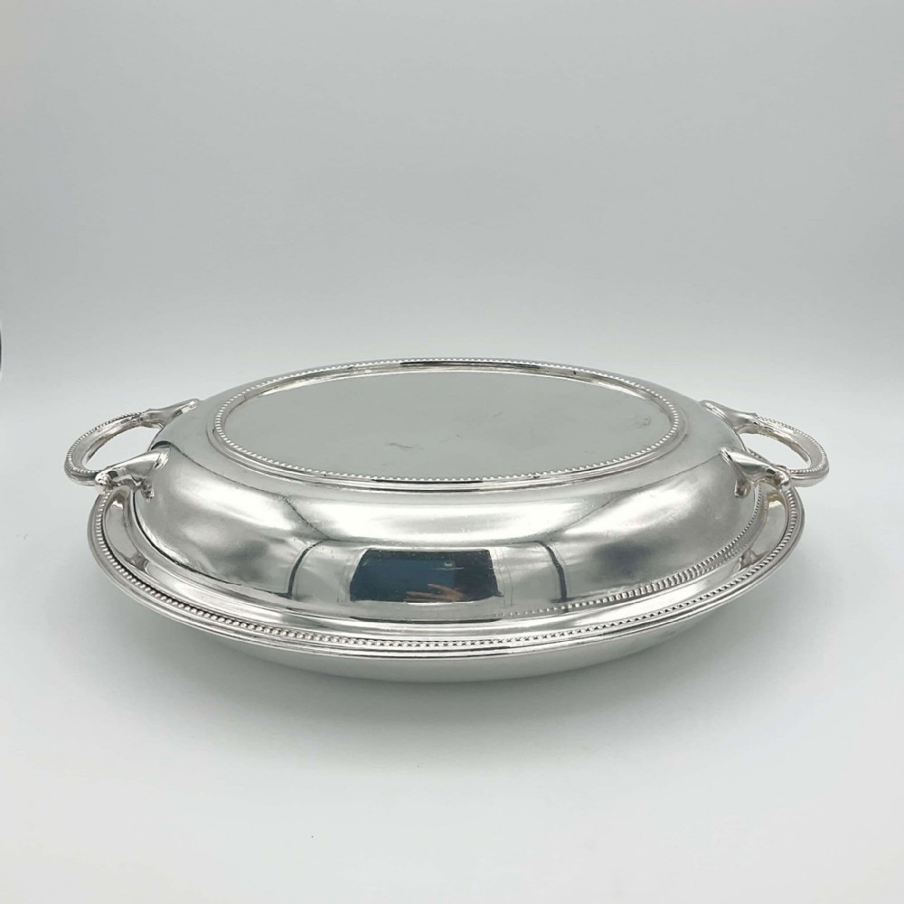 A silver-plated oval entree dish featuring a fitted cover with beaded rim details and two side handles.