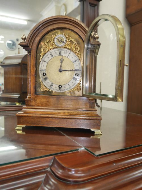 fig 1. An antique arched walnut bracket clock with a brass-mounted silvered dial and corner finials.