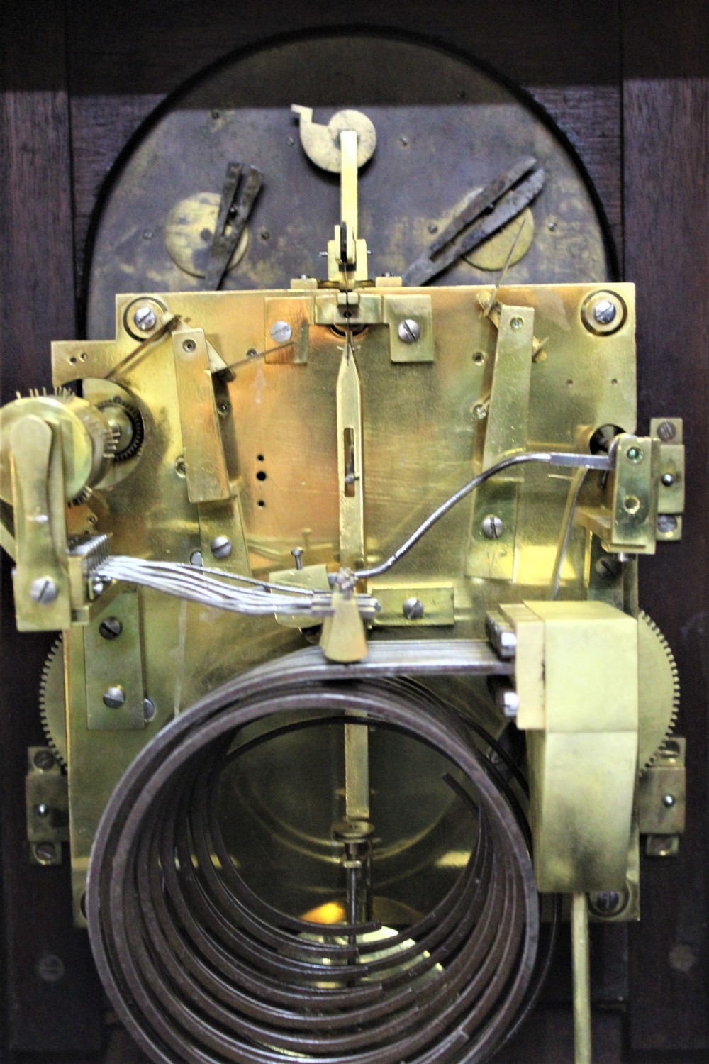 A dark mahogany Edwardian bracket clock featuring brass column supports, pineapple finials, and an ornate silvered dial with subsidiary chime indicators. View V