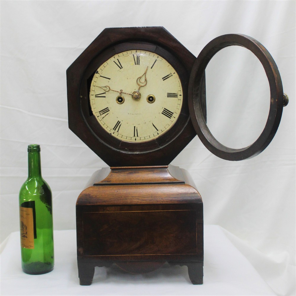 An antique Scottish mahogany mantel clock featuring an octagonal upper head enclosing a cream painted dial with Roman numerals, set on a moulded base with bracket feet. View IV