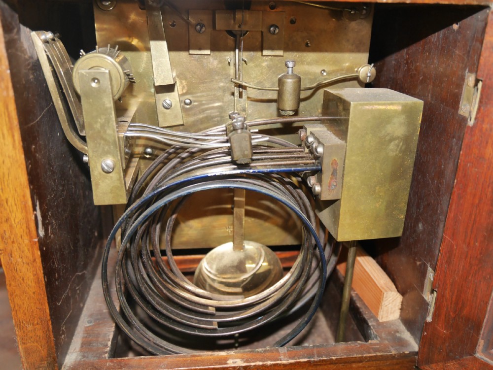 An antique arched walnut bracket clock with a brass-mounted silvered dial and corner finials. View III