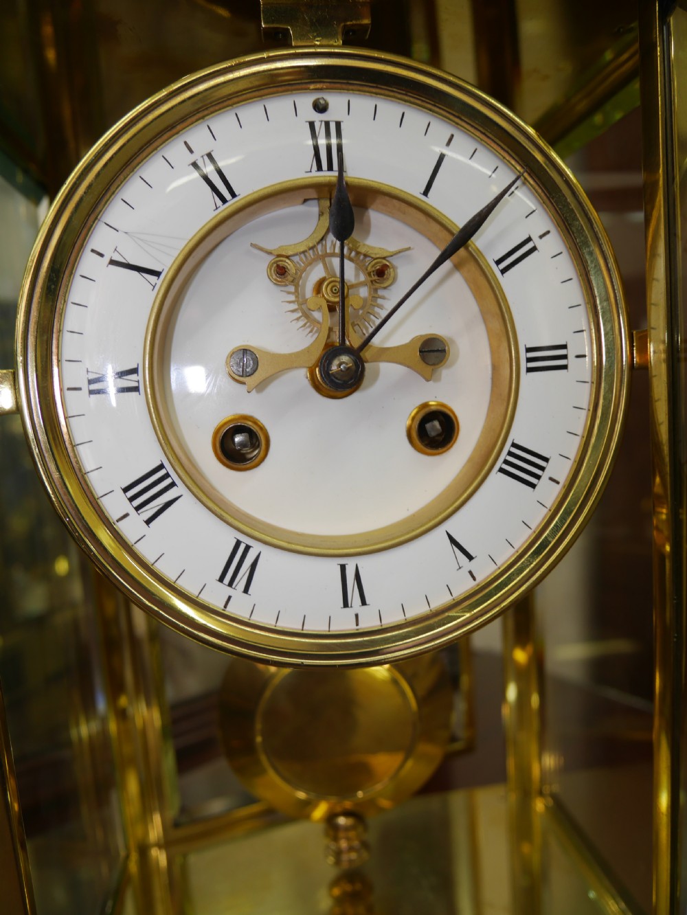 A late nineteenth-century brass four-glass mantel clock featuring a white enamel dial with Roman numerals and a visible brass pendulum. View III