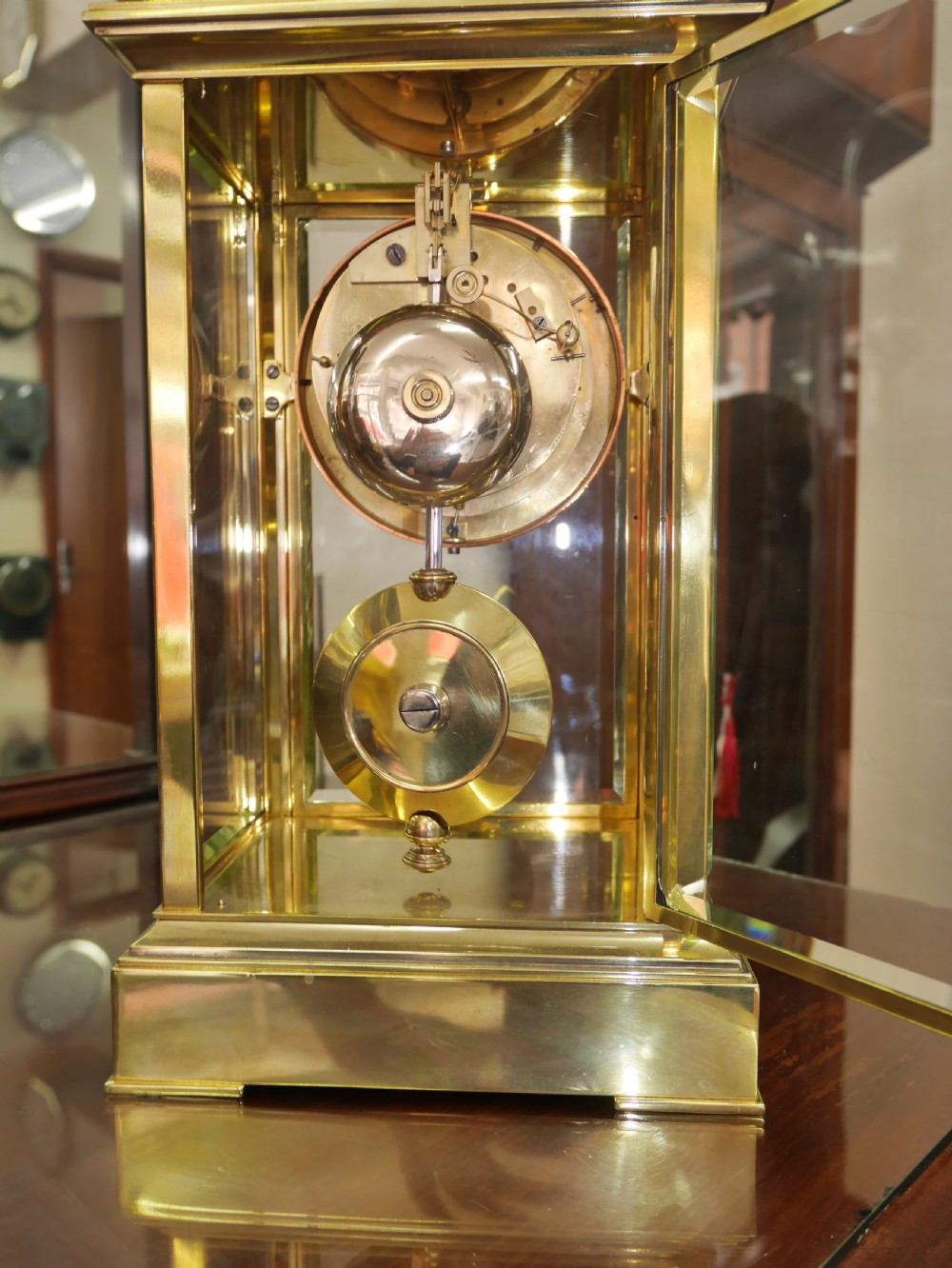 A late nineteenth-century brass four-glass mantel clock featuring a white enamel dial with Roman numerals and a visible brass pendulum. View IV