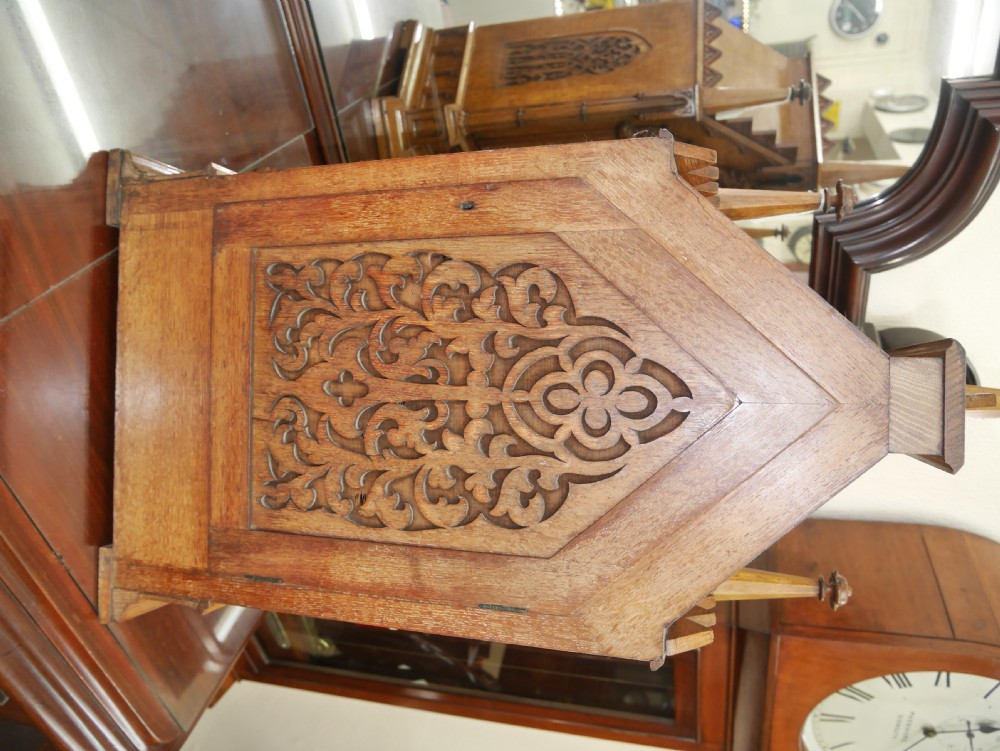 An English Gothic Revival wooden bracket clock featuring carved spires, pointed arches, traceried arcading, and an engraved metal dial signed by John Bennett. View III