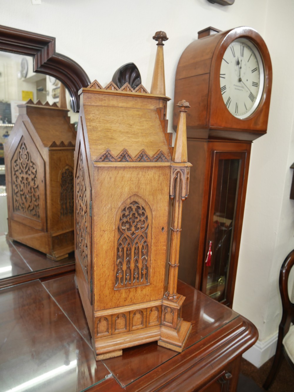An English Gothic Revival wooden bracket clock featuring carved spires, pointed arches, traceried arcading, and an engraved metal dial signed by John Bennett. View V