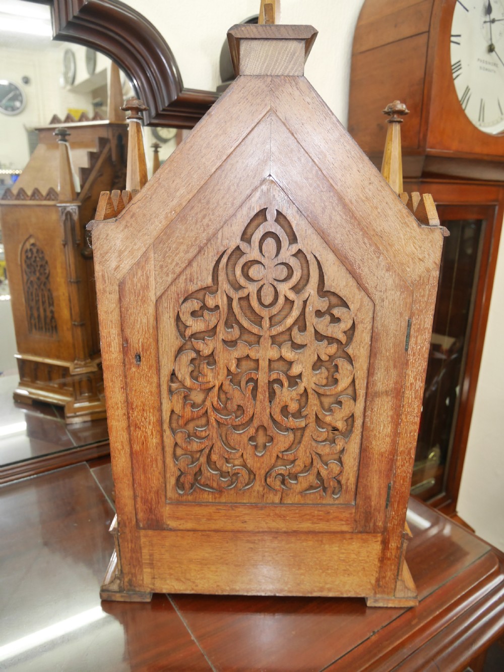 An English Gothic Revival wooden bracket clock featuring carved spires, pointed arches, traceried arcading, and an engraved metal dial signed by John Bennett. View VI