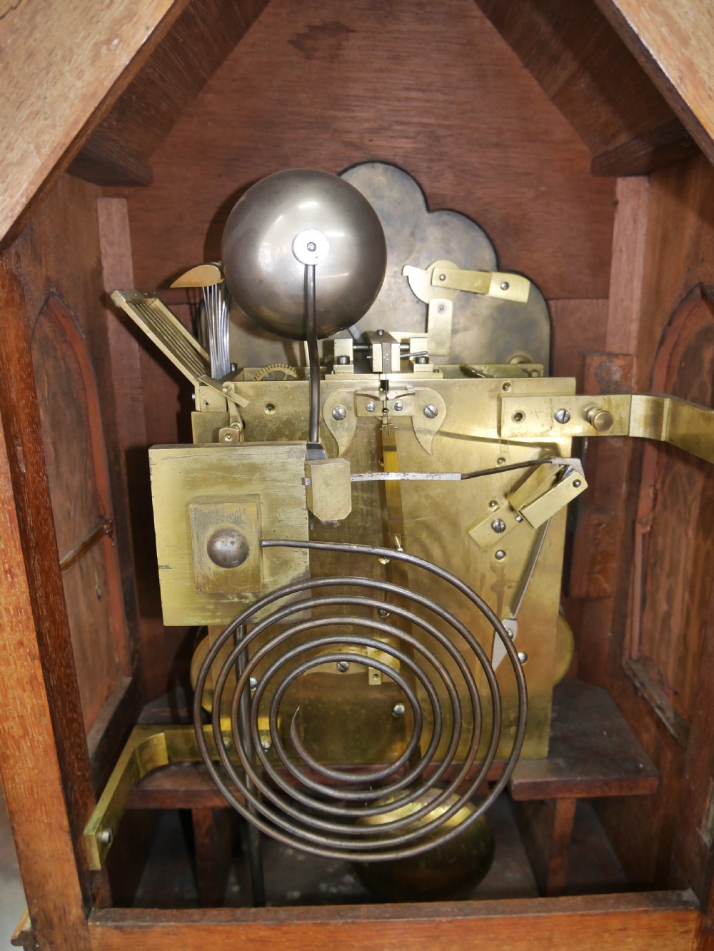 An English Gothic Revival wooden bracket clock featuring carved spires, pointed arches, traceried arcading, and an engraved metal dial signed by John Bennett. View VII