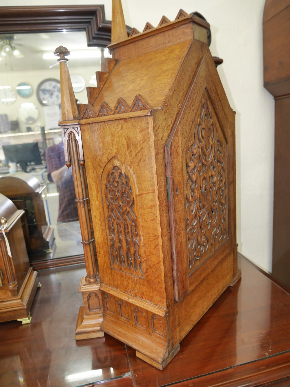 An English Gothic Revival wooden bracket clock featuring carved spires, pointed arches, traceried arcading, and an engraved metal dial signed by John Bennett. View IX