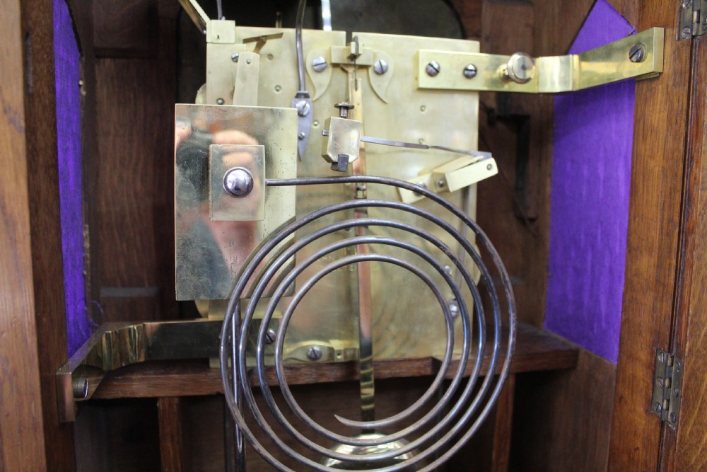 An arched mahogany bracket clock featuring brass spandrels, subsidiary dials, a silvered chapter ring, and brass bracket feet. View II
