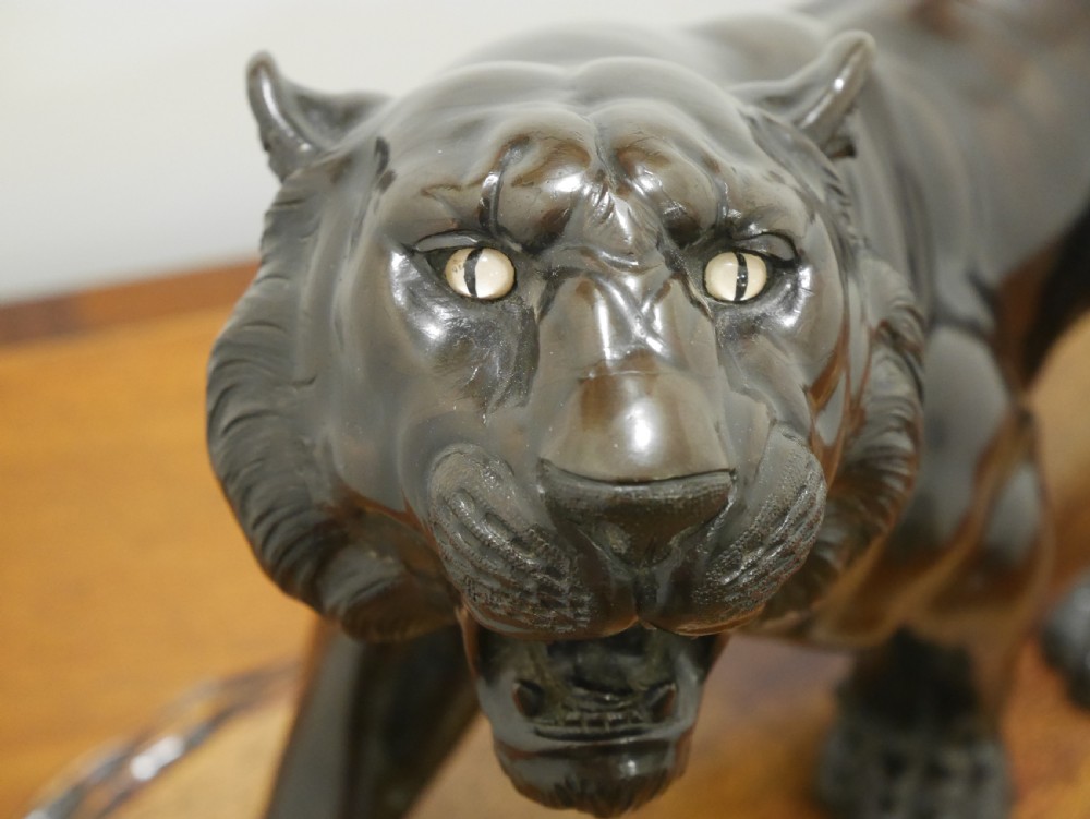 A dark bronze Japanese tiger sculpture depicted in a roaring, prowling stance mounted on a carved wooden base. View II