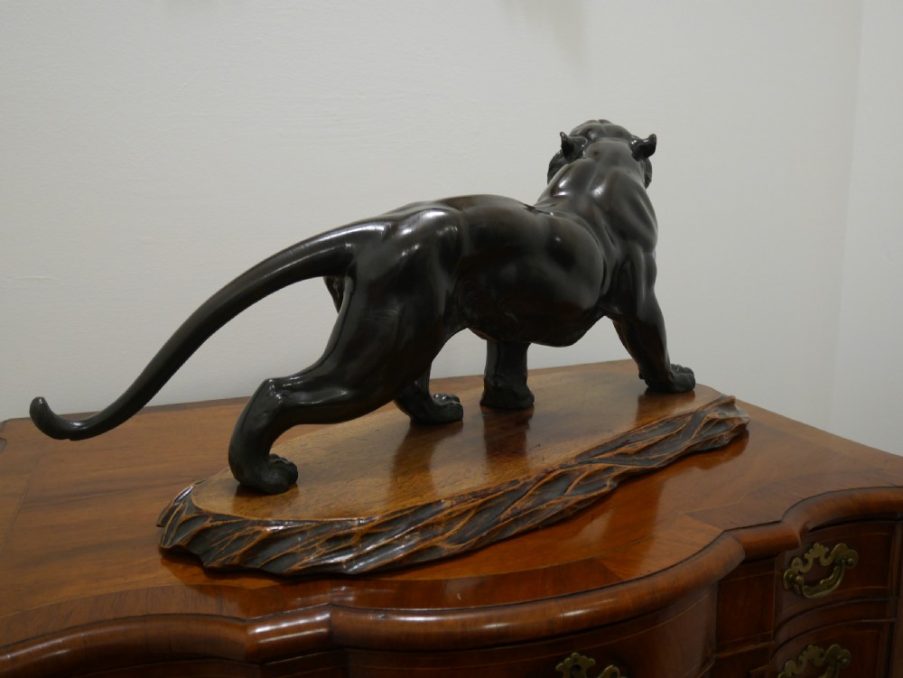 A dark bronze Japanese tiger sculpture depicted in a roaring, prowling stance mounted on a carved wooden base. View III